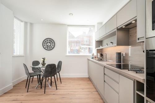 a kitchen with white cabinets and a table and chairs at Citystay Living - Dutch's Corner in Cambridge