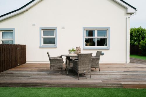 a patio with a table and chairs in front of a house at Modern self catering apartment, Miltown Malbay in Milltown Malbay