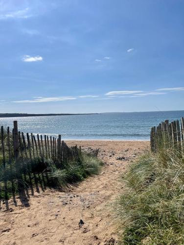 a wooden fence on a sandy beach near the ocean at Modern self catering apartment, Miltown Malbay in Miltown Malbay