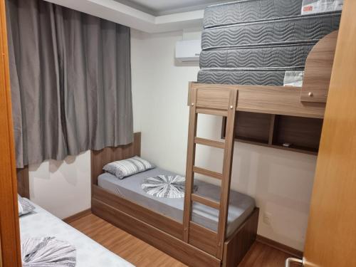 a small bedroom with a bunk bed with a ladder at Conforto em Condomínio Frente Mar in Barra Velha