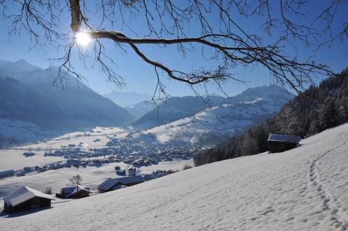 a snow covered hill with the sun shining on a village at Sonnegg Hotel in Zweisimmen