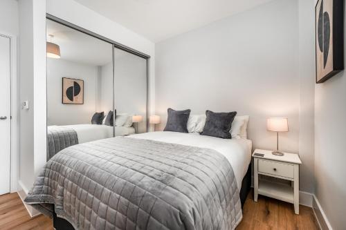a white bedroom with two beds and a mirror at Citystay Living - Dutch's Corner in Cambridge