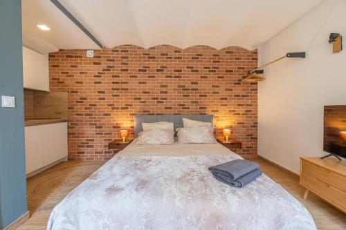 une chambre avec un grand lit et un mur de briques dans l'établissement COSY STUDIO RENOVÉ 150m de MONACO, à Beausoleil