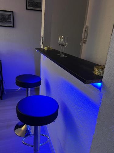 a bar with two blue chairs and a counter with wine glasses at Cocon Accès facile Parking Gratuit in Belfort
