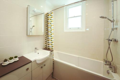 a bathroom with a sink and a tub and a mirror at Stylish, central, adults-only 1-bed Hideaway in Eastbourne