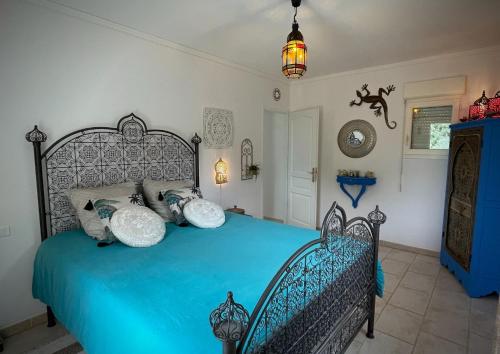 um quarto com uma cama azul com almofadas em Clos Marijeanne Capmas em La Capelle-et-Masmolène