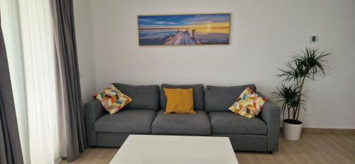 ein Wohnzimmer mit einem grauen Sofa und gelben Kissen in der Unterkunft Bonito apartamento Carvajal - Fuengirola - The Wave in Fuengirola