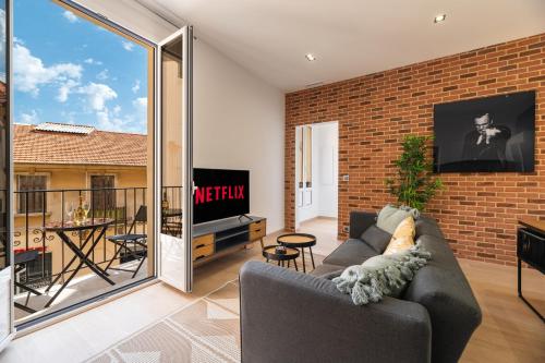 a living room with a couch and a brick wall at SUPERBE APPARTEMENT AVEC BALCON PROCHE MONACO in Beausoleil