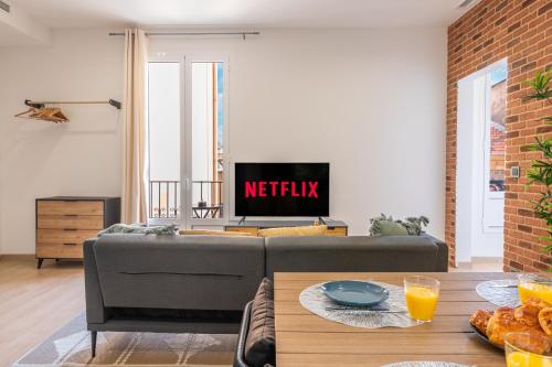 a living room with a couch and a tv at SUPERBE APPARTEMENT AVEC BALCON PROCHE MONACO in Beausoleil