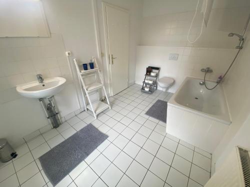 biała łazienka z umywalką i wanną w obiekcie Osthafen IV w Berlinie