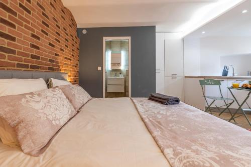 a bedroom with a large bed with a brick wall at CHARMANT STUDIO RENOVÉ 150m DE MONACO in Beausoleil