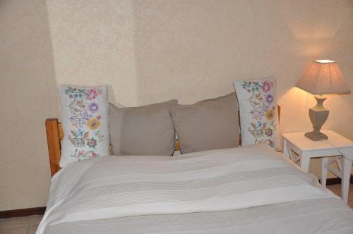 sypialnia z białym łóżkiem z poduszkami i lampą w obiekcie Appartement dans la vieille ville, en face du château w Annecy