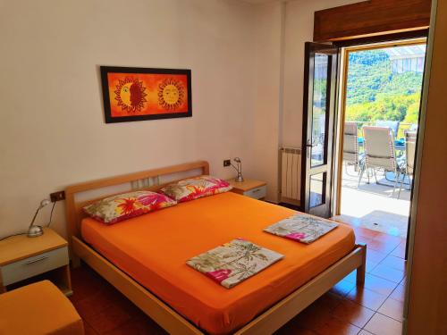 una camera da letto con un letto con lenzuola arancioni e un balcone di Residence Casa Silvana a Tignale
