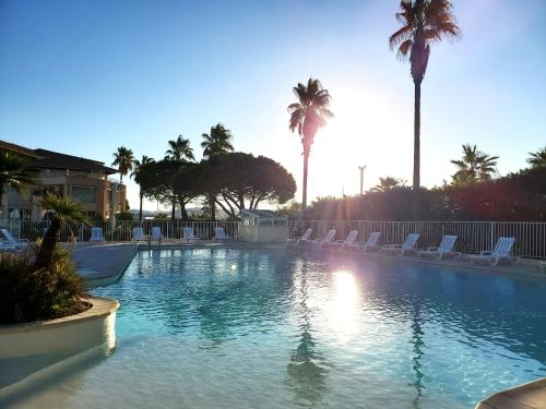 une grande piscine avec chaises et palmiers dans l'établissement CAP HERMES Vue MER Magnifique logement 6 couchages, à Fréjus
