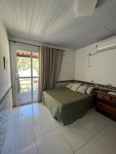 a bedroom with a bed and a large window at MARAGOGI FLAT BEIRA MAR in Maragogi