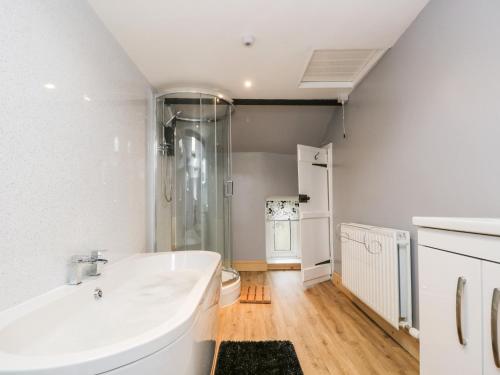 a white bathroom with a tub and a toilet at Fellside Cottage in Cockermouth