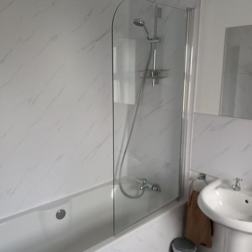 een glazen douche in een badkamer met een wastafel bij The Tardis, Portstewart Town in Portstewart