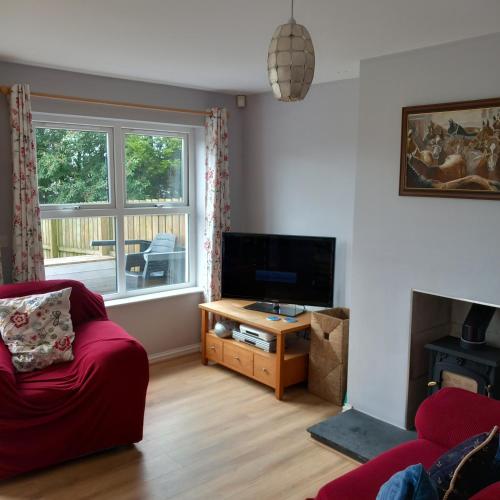een woonkamer met een rode bank en een televisie bij The Tardis, Portstewart Town in Portstewart