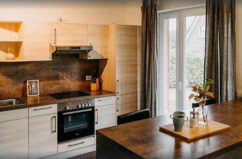 a kitchen with white cabinets and a table with a stove at Haus Hilde Zarrentin am Schaalsee in Zarrentin