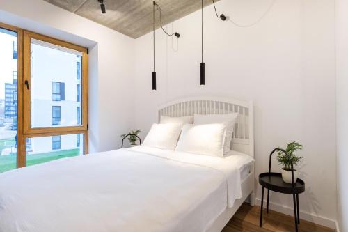 a white bedroom with a white bed and a window at City Center Sanctuary Modern Studio with Electric Car-Friendly Features in Vilnius in Vilnius