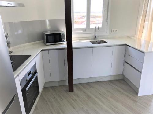 a white kitchen with a sink and a microwave at Luxury Attics Plaza Punto PARKING INCLUIDO in Huelva