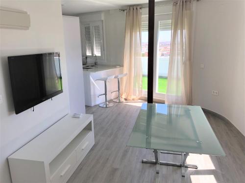 uma sala de estar com uma televisão e uma mesa de vidro em Luxury Attics Plaza Punto PARKING INCLUIDO em Huelva