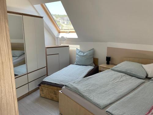 a attic bedroom with two beds and a mirror at Jasmin Apartment House in Vonyarcvashegy