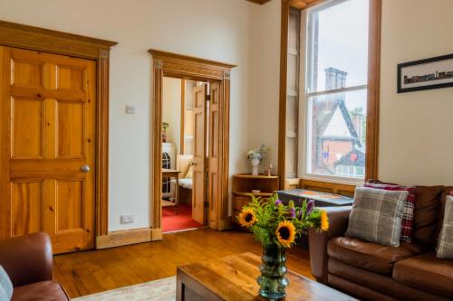 una sala de estar con sofá y un jarrón de flores sobre una mesa en Beautiful Grade II listed apartment., en Leek