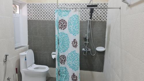 a bathroom with a toilet and a shower curtain at Sadaf Hotel Apartments in Sohar