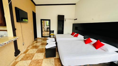 ヒウテペックにあるHotel Villa Pralayaの赤い枕が備わる客室内のベッド2台