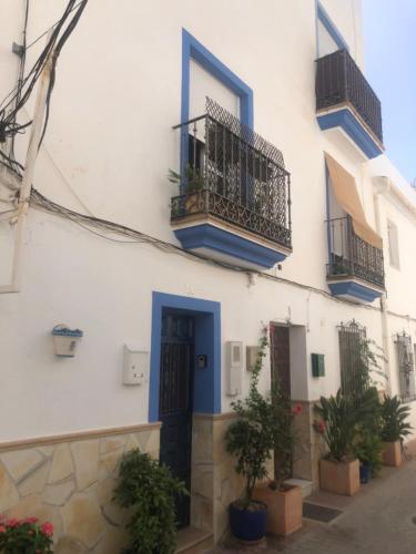 a white building with blue doors and windows and potted plants at Casa D’Amelia in Ojén