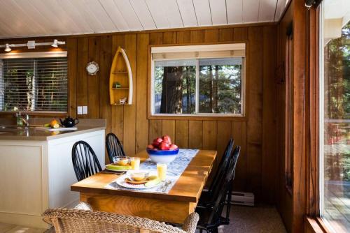 a dining room with a table and chairs and a kitchen at Evergreen Cottage in Bowen Island