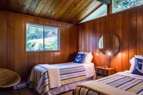 a bedroom with two beds and a window at Evergreen Cottage in Bowen Island