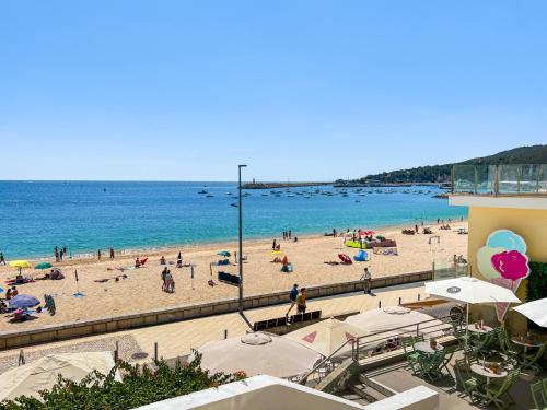 a beach with a bunch of people on it at Sea View Apartment, Steps from the Beach, Sesimbra in Sesimbra