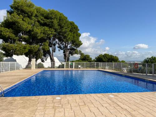 a blue swimming pool with a tree in the background at Apartamento Aventura in Salou