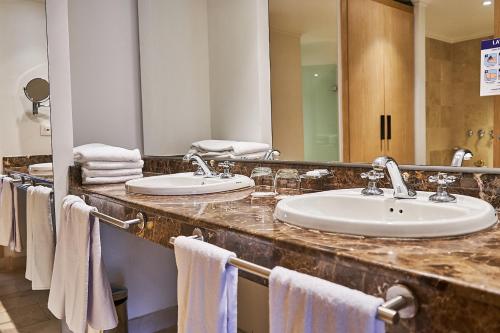 a bathroom with two sinks and a mirror and towels at Hotel Poblado Plaza in Medellín