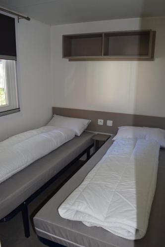 two beds sitting in a room with a window at Mobilhome 526 3ch/2SDB camping 4* La Réserve SIBLU Gastes in Gastes