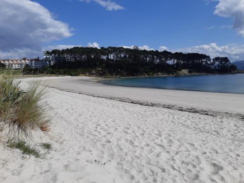 a beach with footprints in the sand and water at Apartamento Alba in Portonovo