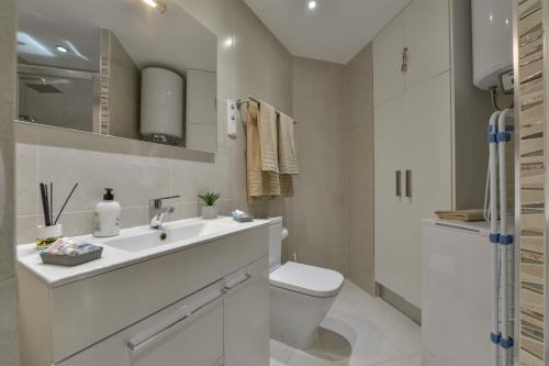 a white bathroom with a toilet and a sink at Estudio Loft Horizonte Playa Fossa Calpe in Calpe