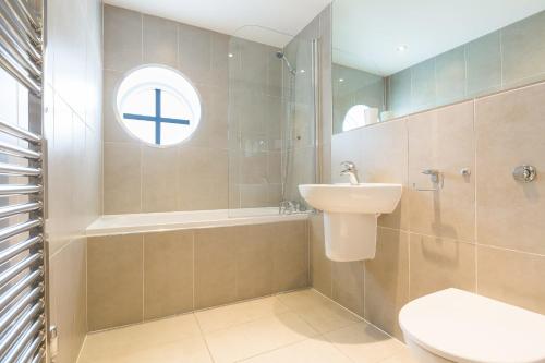 een badkamer met een wastafel, een toilet en een raam bij Serendipity in St Ives