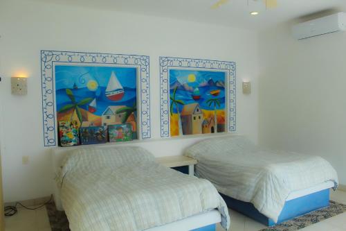 um quarto com duas camas e pinturas na parede em Villa Santorini em Uaymitun