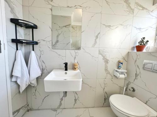 Cape Town的住宿－Big Bay Beach Front Estate Apartment，白色的浴室设有水槽和卫生间。