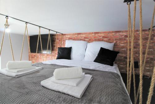 1 cama con almohadas blancas y pared de ladrillo en Jacuzzi na dachu, en Rzeszów