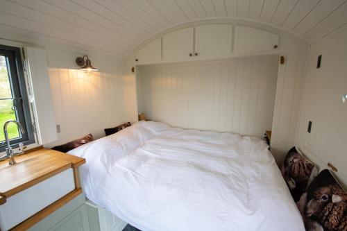 um quarto com uma cama branca num quarto em Shepherds Hut em Lonmore