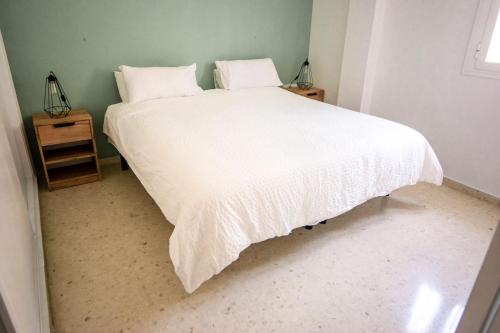 una camera con letto bianco e comodino di Apartament New Cathedral a Siviglia