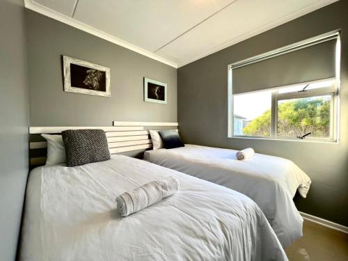 two beds in a room with a window at Big Bay Beach Front Estate Apartment in Cape Town
