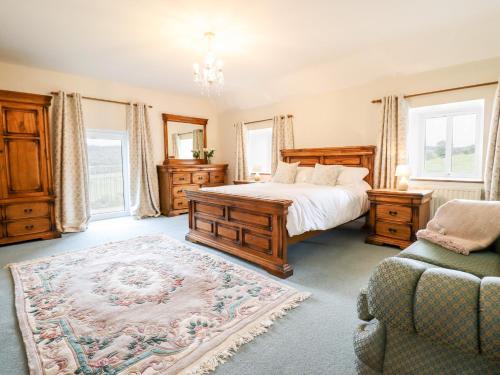 a bedroom with a bed and a couch and windows at The Stables At Cae Gwyn in Ruthin