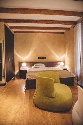 a bedroom with a bed and a green chair at Heritage Hotel Kukuriku in Kastav