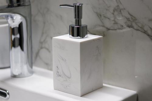 - un distributeur de savon blanc assis sur un lavabo dans l'établissement Albatross Volos Luxury Apartment, à Vólos