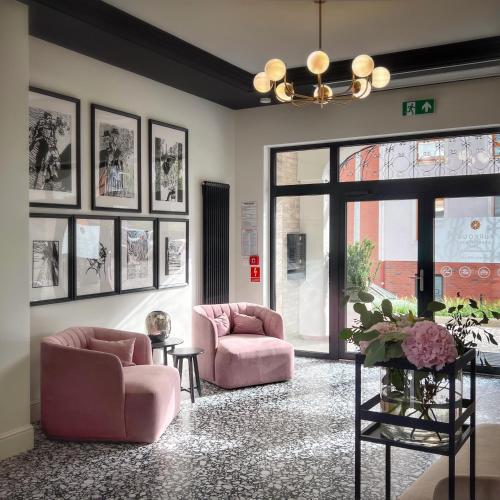 a lobby with two pink chairs and a large window at Kurkowa Apartments in Szczecin